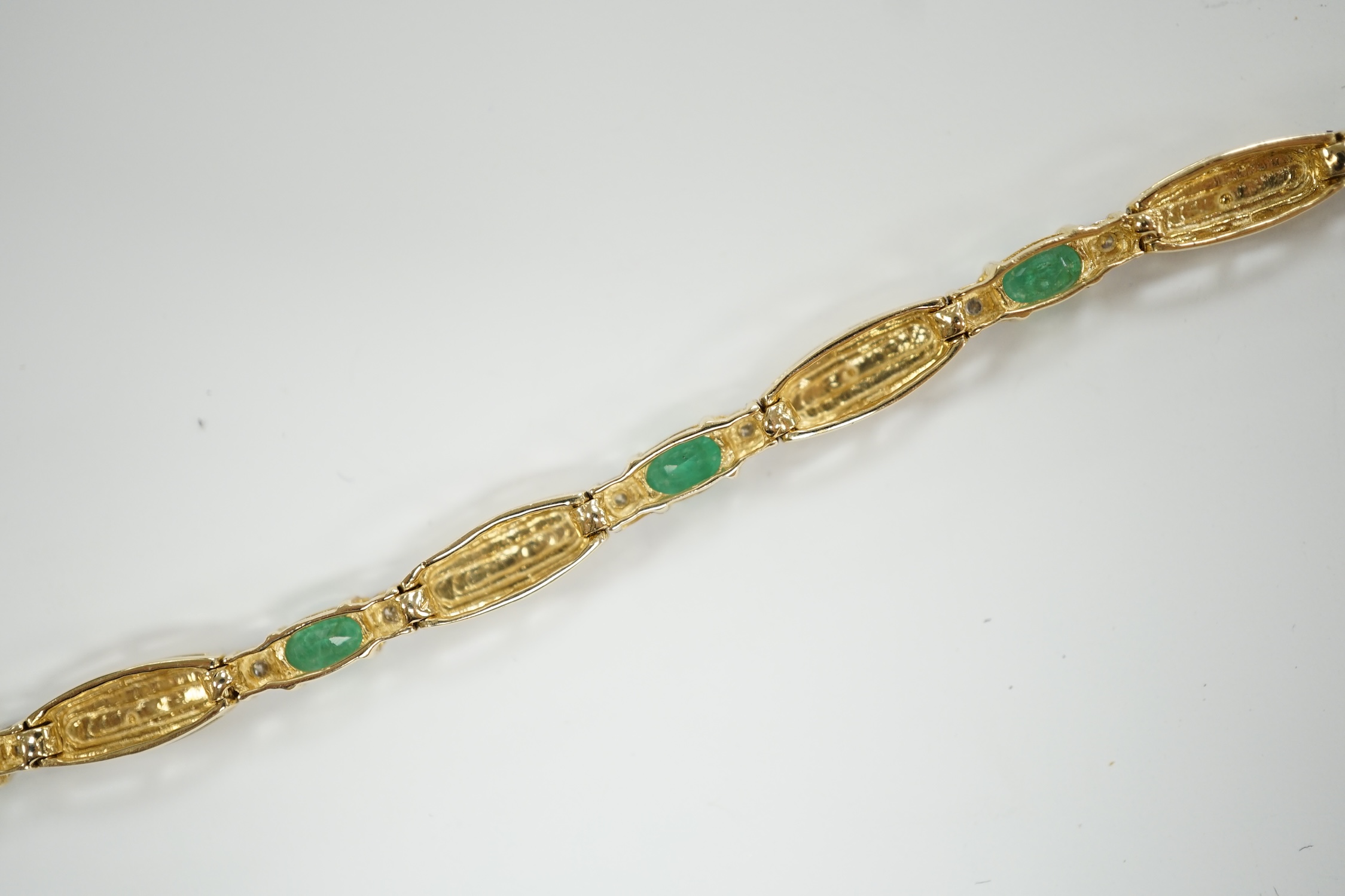 A modern yellow metal, emerald and diamond chip cluster set bracelet, 17.7cm, gross weight 7.6 grams.
